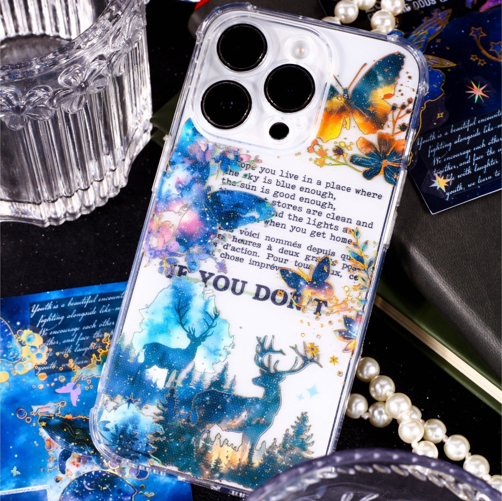 StationeryHaul Celestial Galaxy stickers with deer, butterflies, and text on a clear phone case.