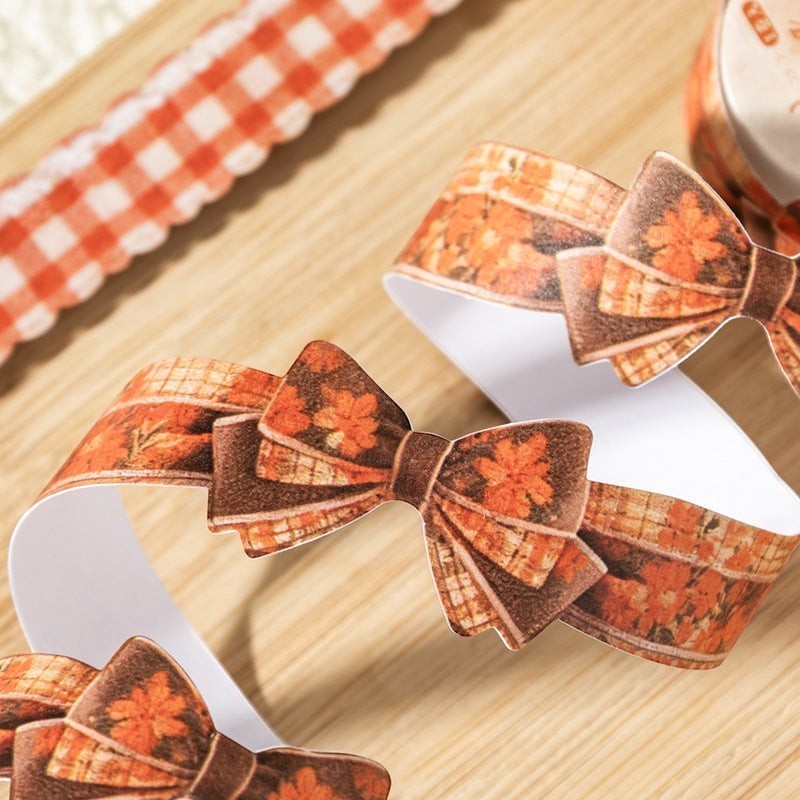 StationeryHaul decorative craft ribbon featuring orange floral patterns and pre-tied bow accents on a wooden surface