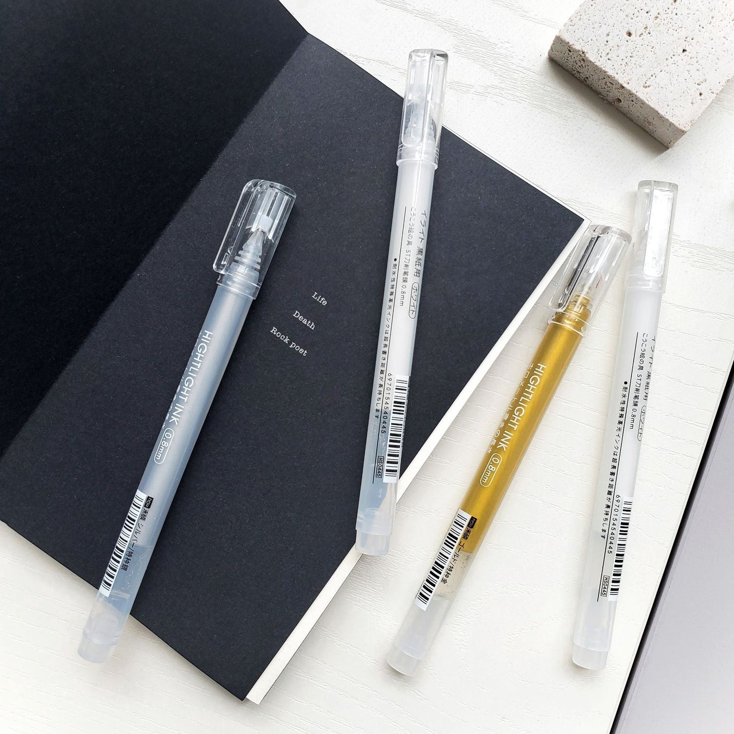 StationeryHaul Metallic Highlighter Pen Set with fine tips in gold, silver, and white colors on a black notebook.