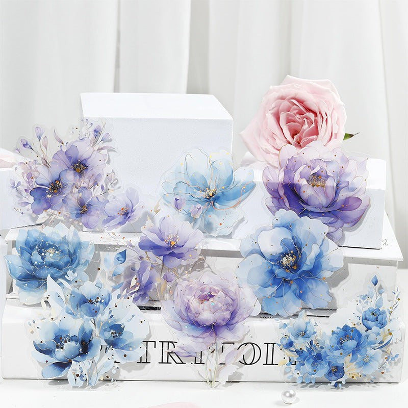 StationeryHaul watercolor floral stickers in blue, purple, and pink with gold foil accents. Translucent, waterproof, artistic design.