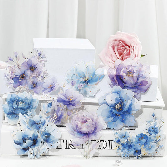 StationeryHaul watercolor floral stickers in blue, purple, and pink with gold foil accents. Translucent, waterproof, artistic design.