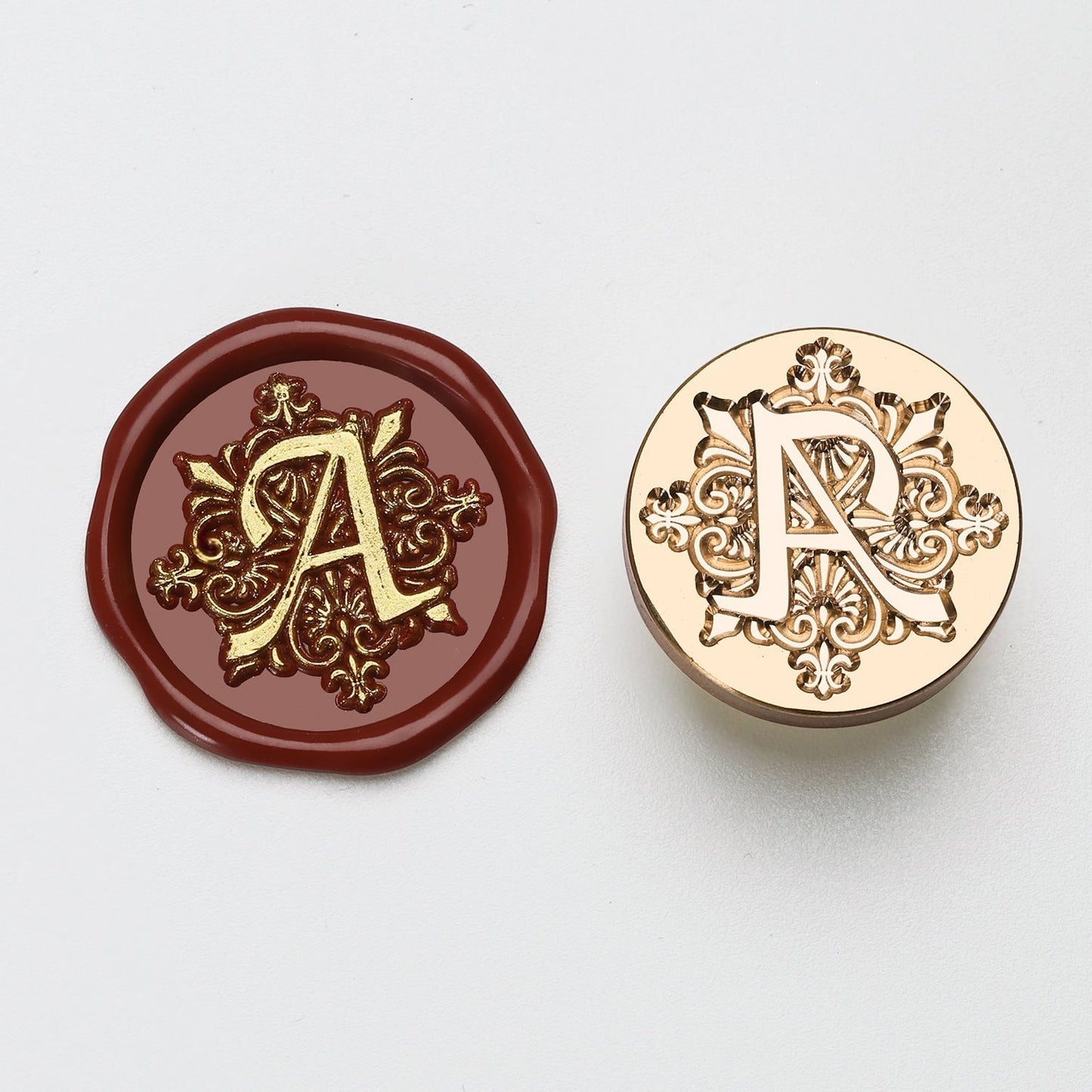 StationeryHaul elegant brass wax seal stamp with ornate letter A design, next to a burgundy wax impression.