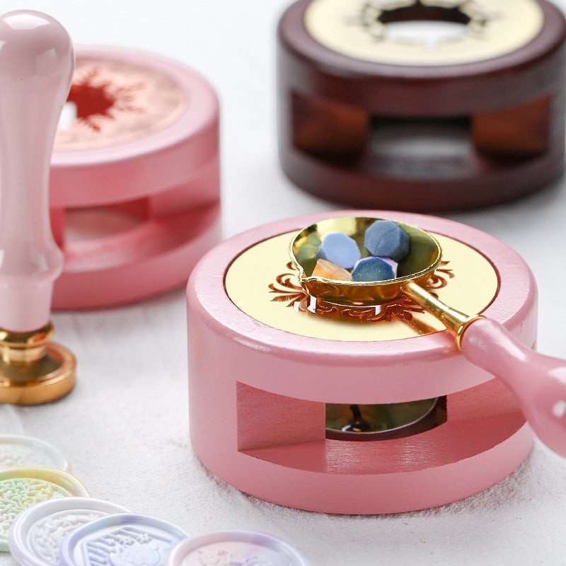 StationeryHaul pink wax seal stamp warmer with gold accents and a spoon of colorful wax beads.